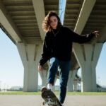 woman in black long sleeve shirt and blue denim jeans jumping on green grass field during
