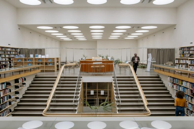 black man with book near stairs in public library