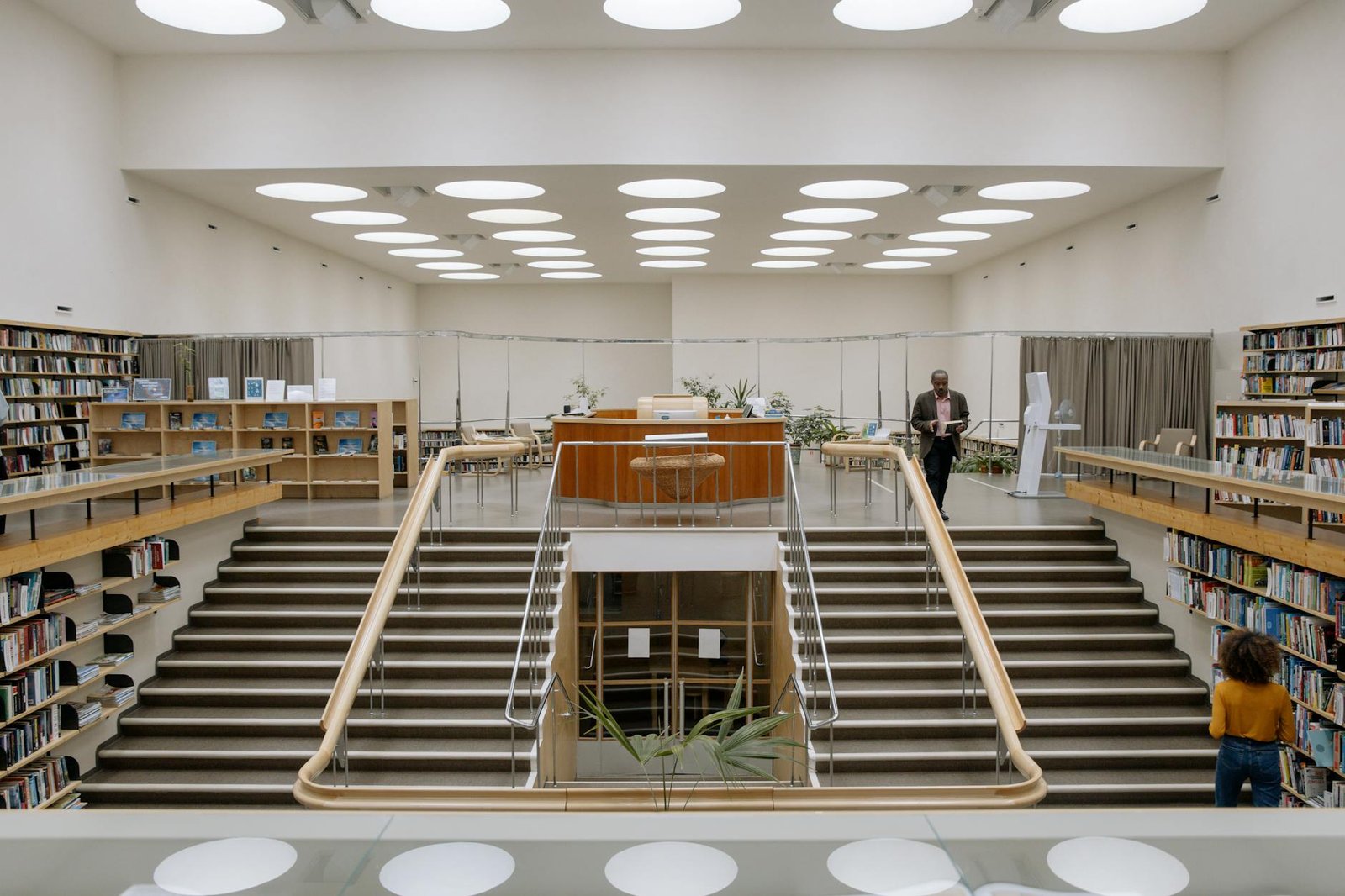 black man with book near stairs in public library