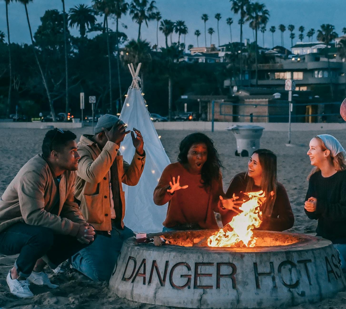 group of friends sitting in front of fire pit