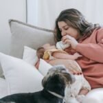 woman feeding infant baby near dog
